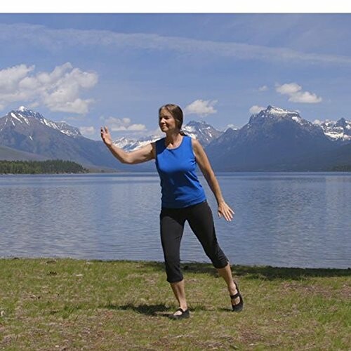 Woman exercising by a lake with mountains in the background